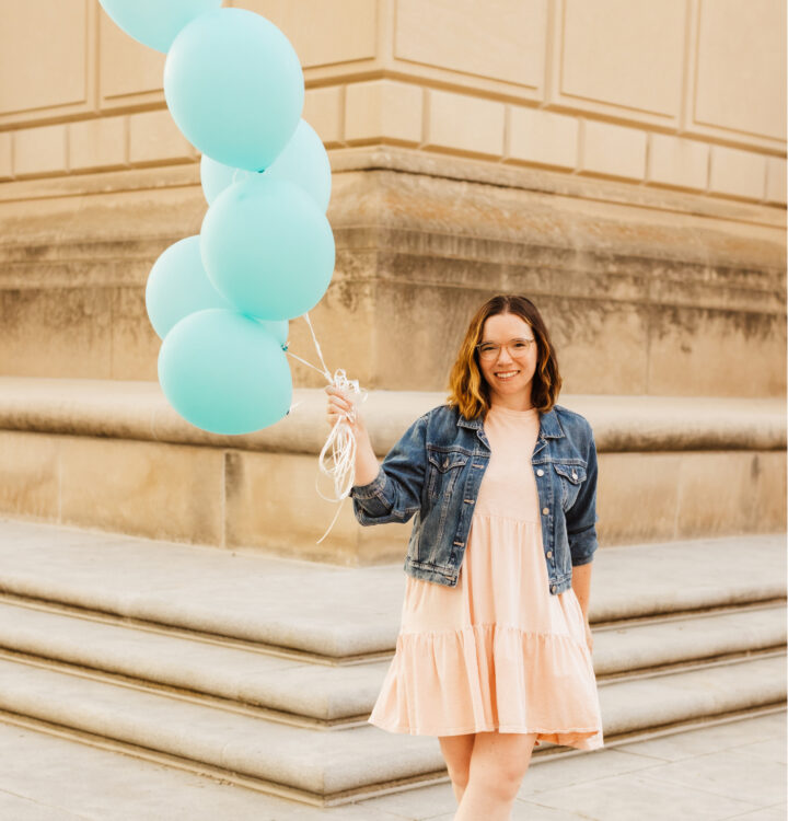 Hannah Replogle, HR recruiter, holding blue balloons in front of an Indianapolis building