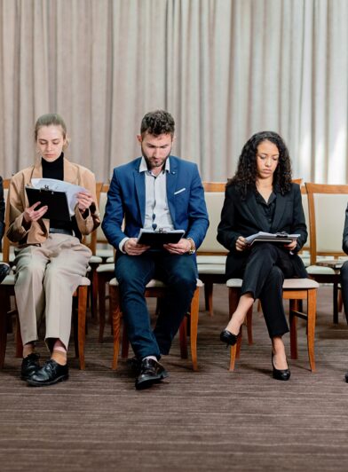 A group of 5 candidates sit side by side in an office